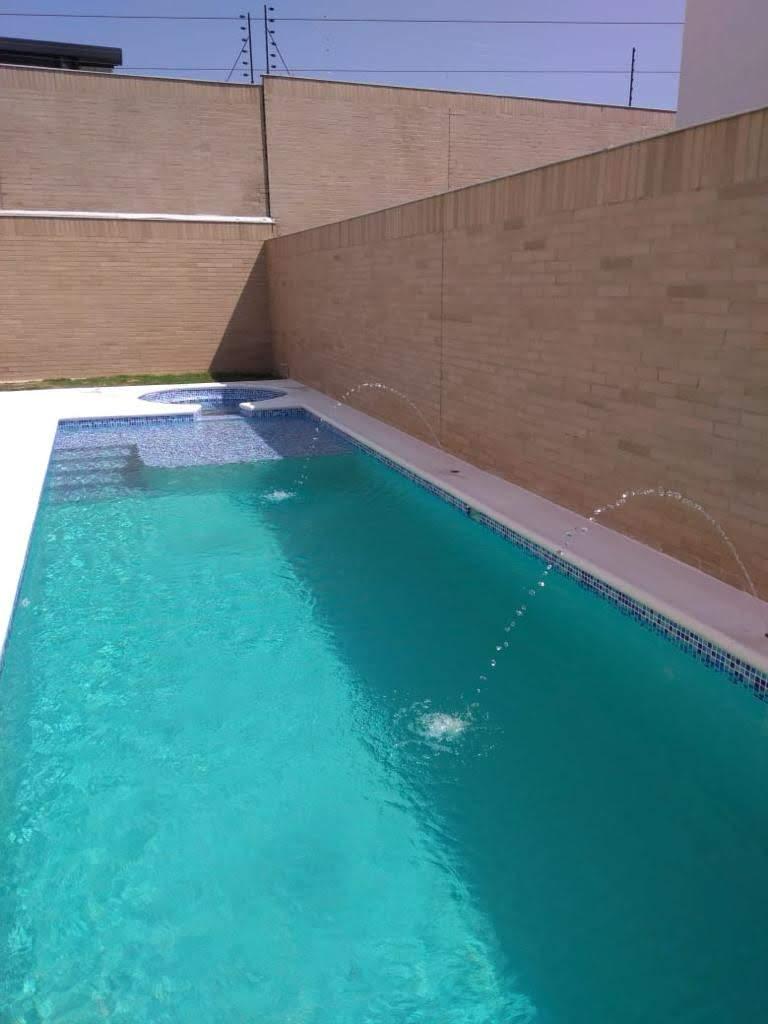 Piscina residencial con fuentes y muro en ladrillo