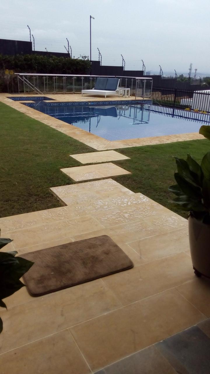 Andenes perimetrales y accesos en piedra renovados alrededor de una piscina residencial, como parte de una reparación de ArquiPiscinas